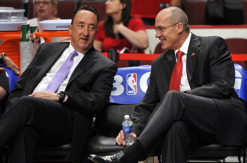 Chicago Bulls executives Gar Forman and John Paxson talk on the bench.