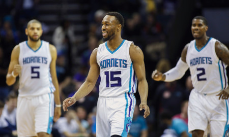 Charlotte Hornets guard Kemba Walker, center, smiles as teammates Nicolas Batum, left and Marvin Williams look on after Walker hit a 3-pointer in the closing seconds against the New Orleans Pelicans in the second half of an NBA basketball game in Charlotte, N.C., Wednesday, March 9, 2016. Charlotte won 122-113. (AP Photo/Nell Redmond)